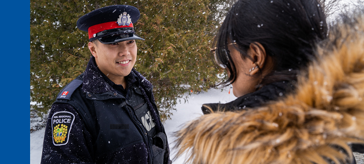 Asian male police officer smiling at citizen