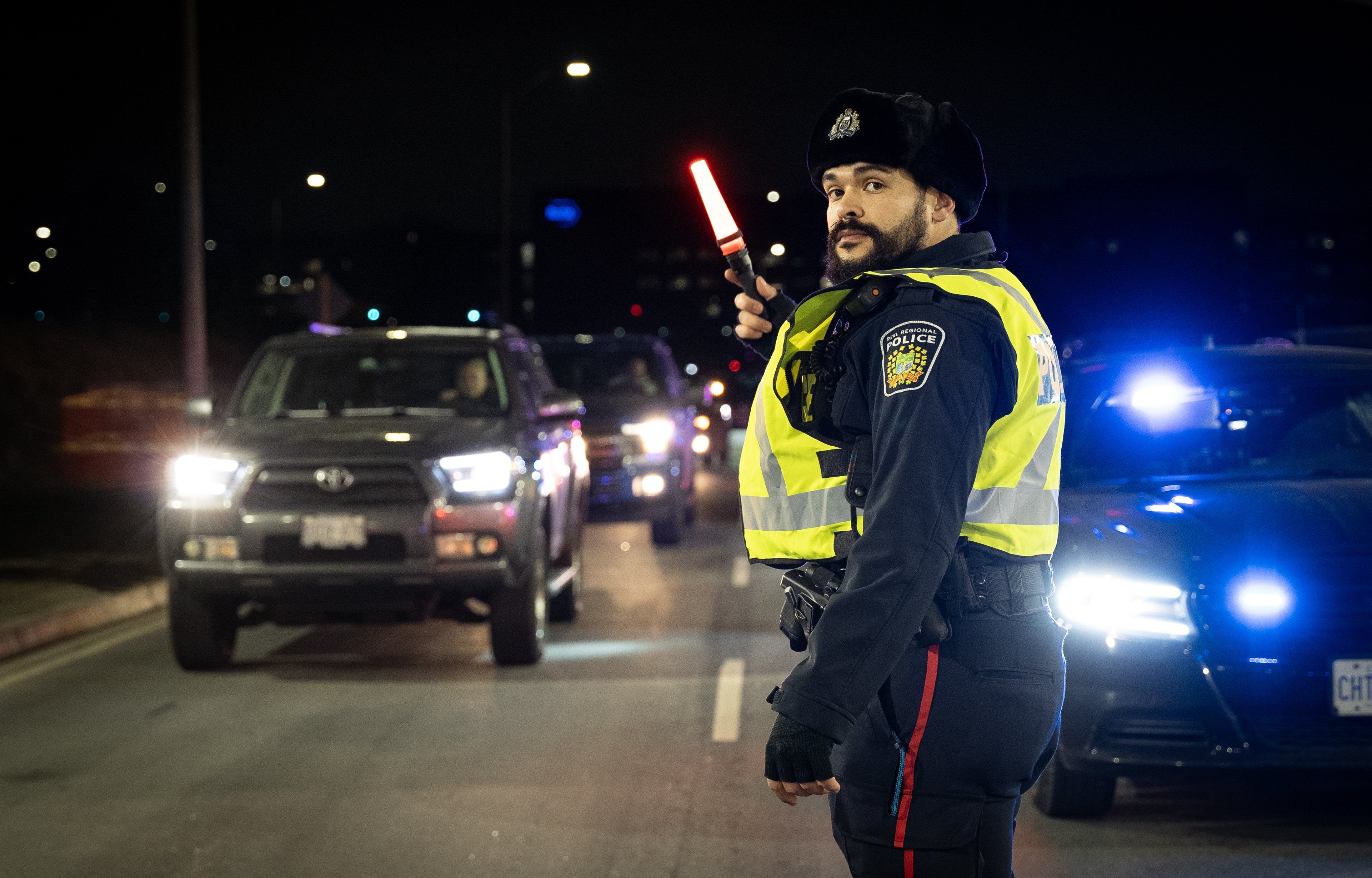 Police officer guiding traffic at night